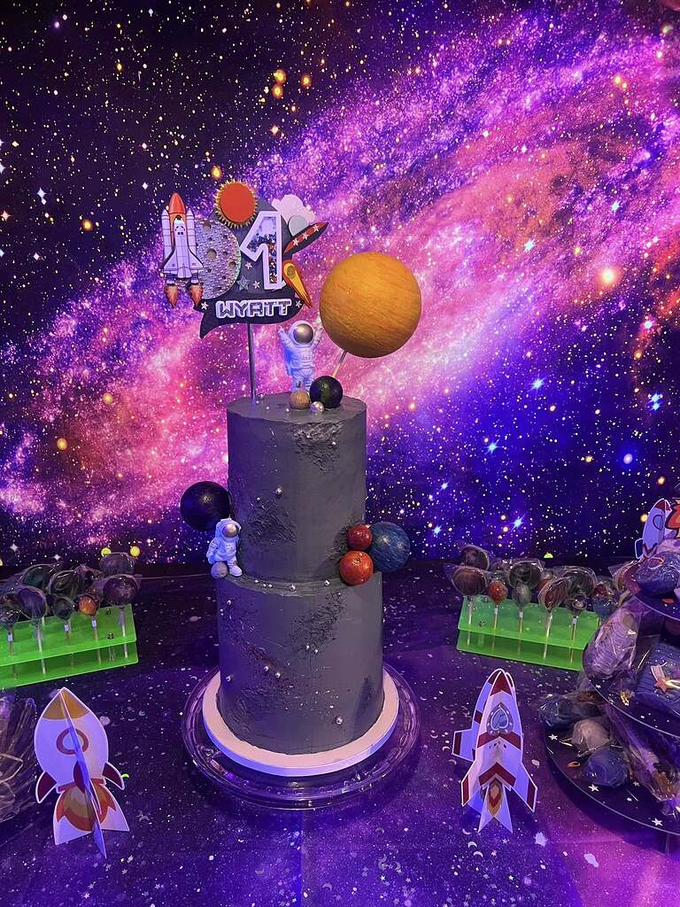 Two-tier space-themed birthday cake for Wyatt aged one, featuring astronaut and planet decorations.
