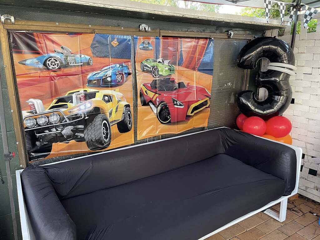 Hot Wheels themed birthday party decoration featuring racing wall banners and a Large black number three balloon.