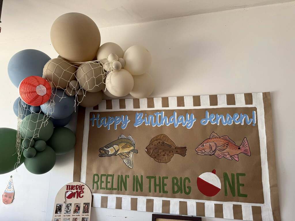 Happy Birthday Jensen fishing-themed banner with neutral-toned balloon arch and decorative fishing net.