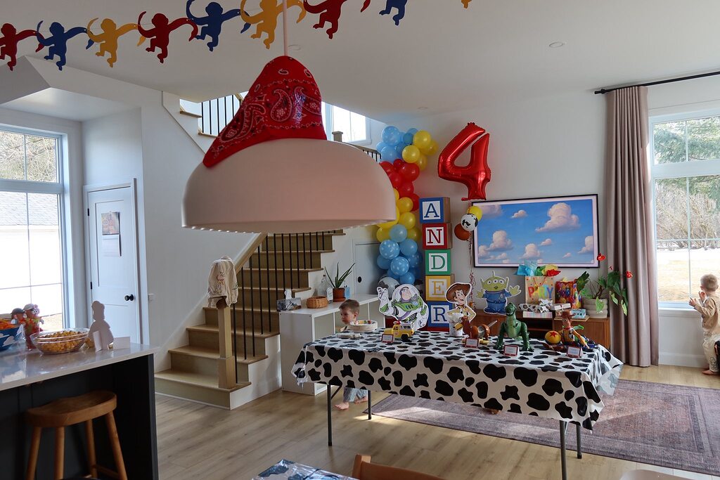 Toy Story themed birthday party setup with a cow print tablecloth and character cutouts in a living room.