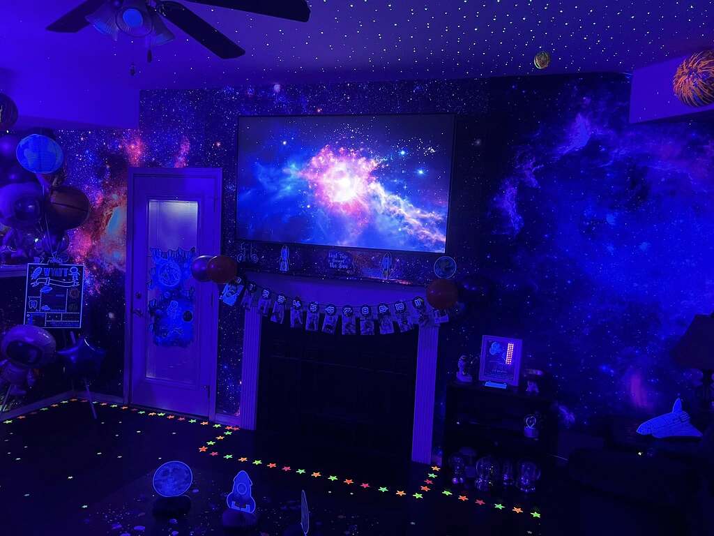 Space-themed room with galaxy wallpaper, glow-in-the-dark stars, and a television displaying a nebula.
