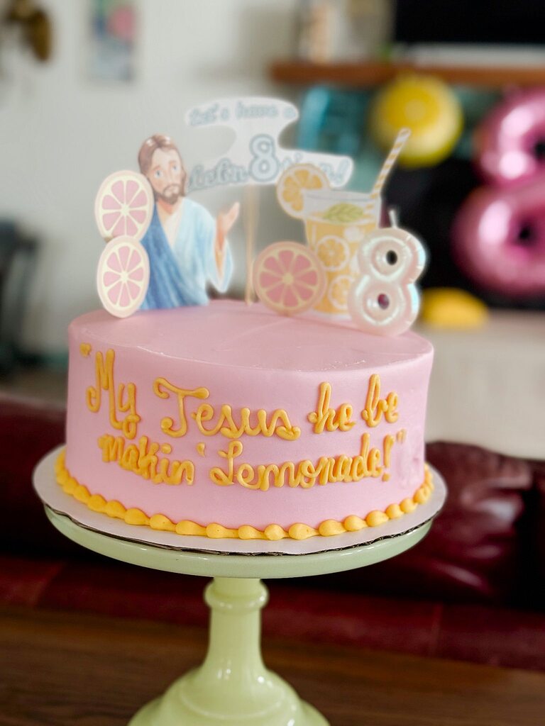 Pink birthday cake topped with Jesus and lemonade decorations for an 8th birthday celebration.