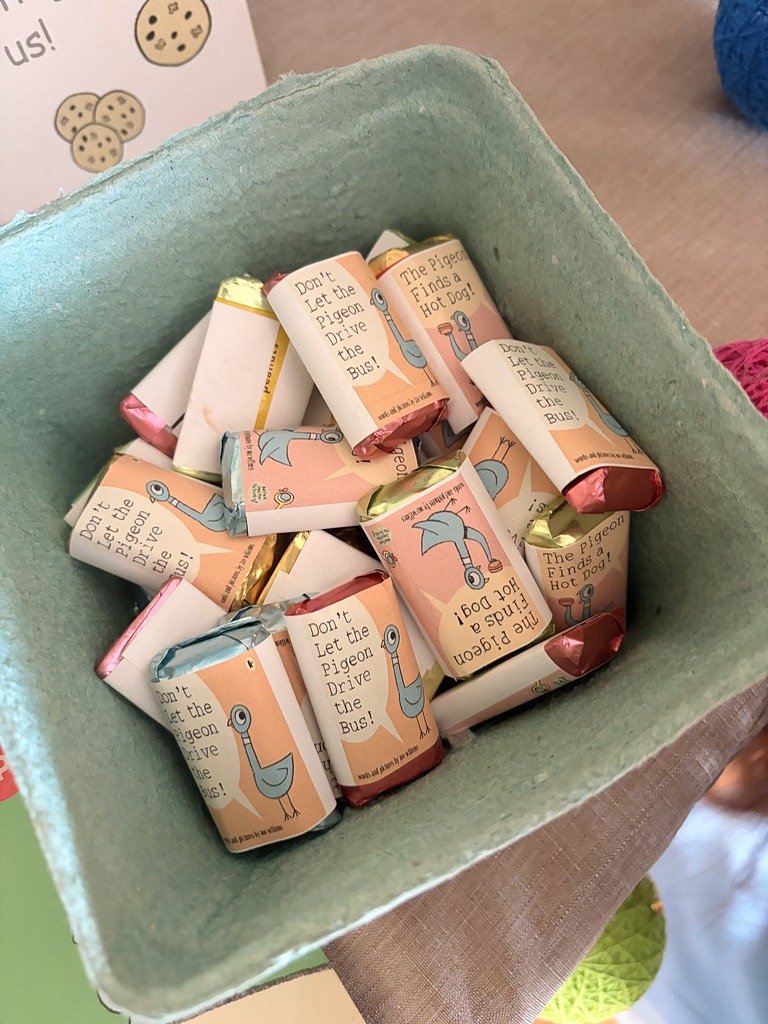 A basket filled with mini candy bars labeled with Don't Let the Pigeon Drive the Bus! book covers.
