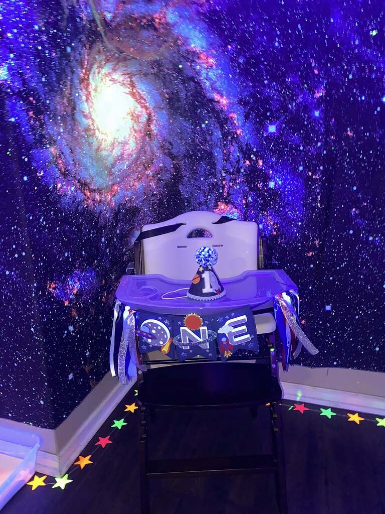 Space-themed first birthday high chair banner and matching party hat for a baby's first birthday celebration.