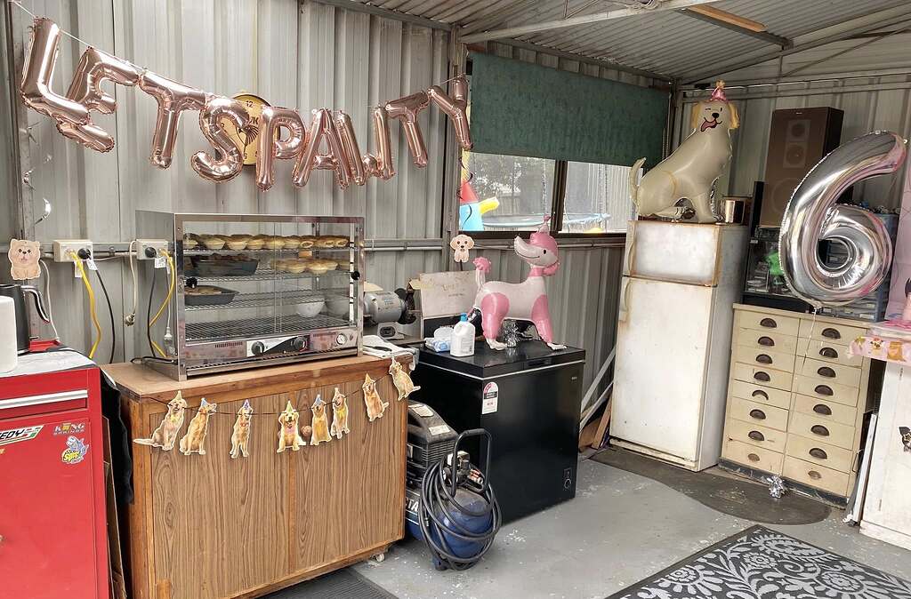 Garage workshop decorated with dog-themed party balloons and birthday banners for a celebration.