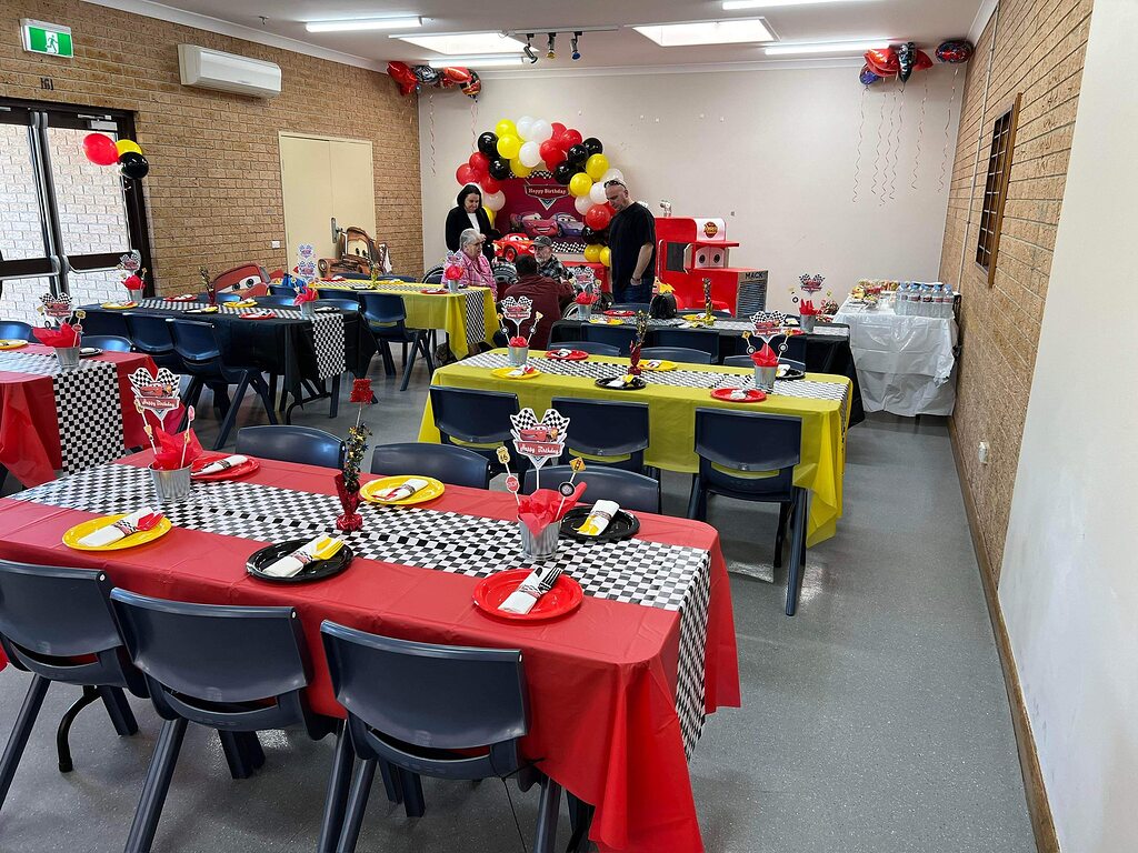 Community hall decorated for a Cars-themed birthday party with red and yellow checkered tables.