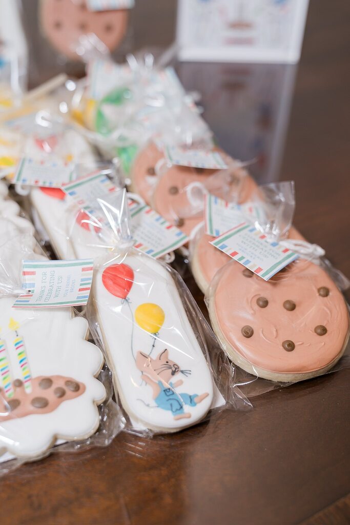 Individually wrapped party favor cookies with birthday-themed icing and hanging thank you tags.