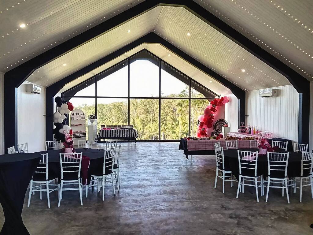 Event space featuring Sephora-themed party decorations, black and pink decor, and circular tables with white chairs.