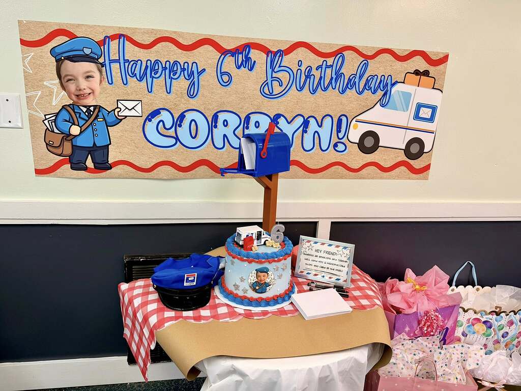 Mail carrier themed 6th birthday party setup with custom banner, cake, and post office box centerpiece.
