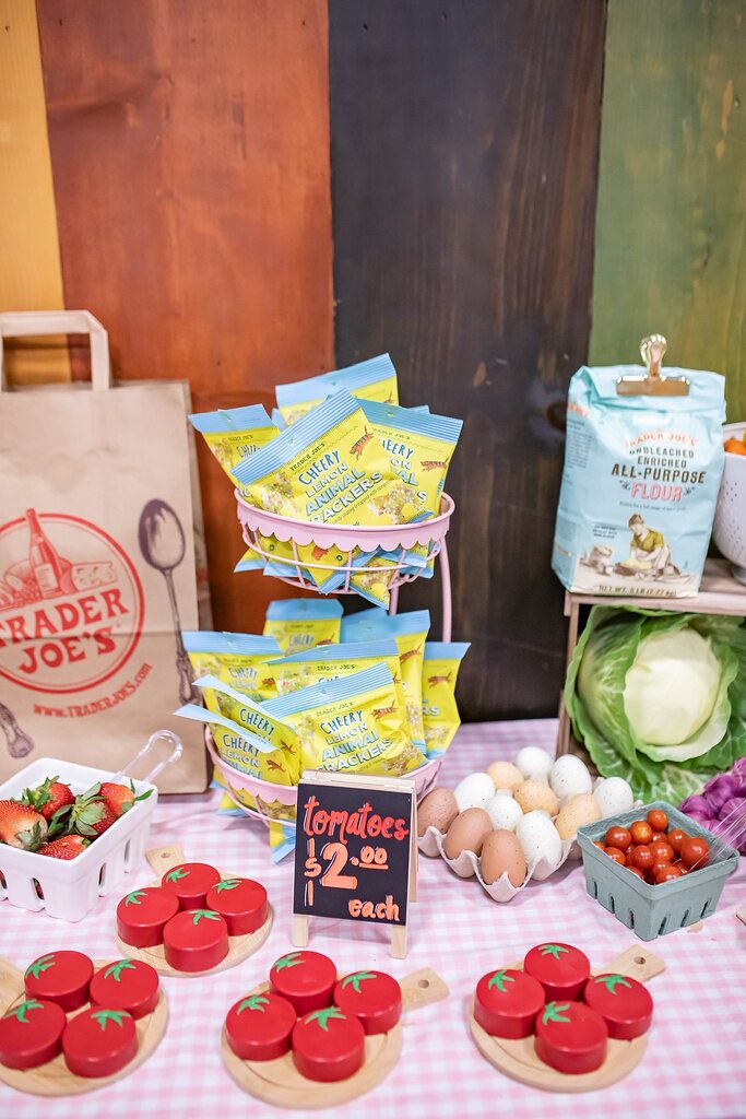 Table display featuring Trader Joe's Cheery Lemon Animal Crackers, all-purpose flour, strawberries, and toy tomatoes.