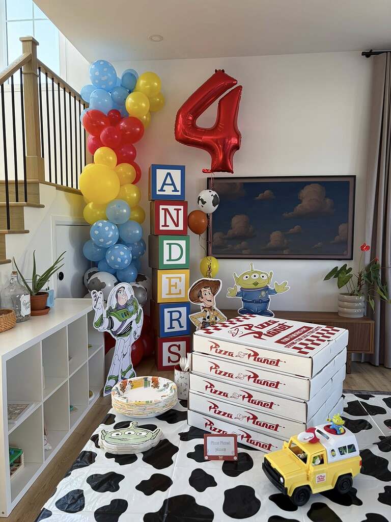 Toy Story themed birthday party setup with stacked Pizza Planet boxes and decorative character cutouts
