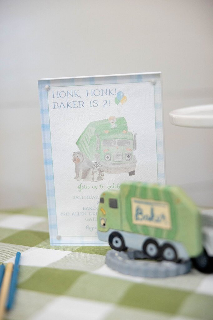 Tabletop sign for a second birthday party featuring a cartoon garbage truck and animals with the text Honk Honk Baker Is 2