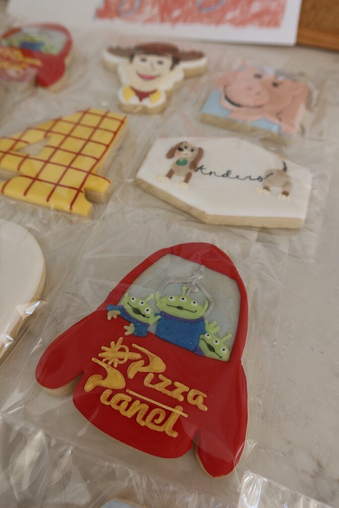 Decorated sugar cookies featuring Toy Story themes, including a Pizza Planet rocket and characters.