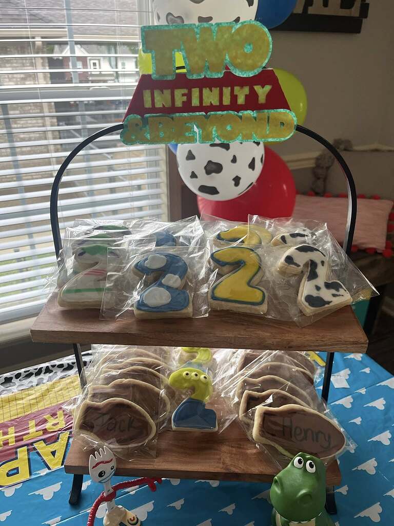 Toy Story inspired number two cookies displayed on a tiered wood tray for a second birthday party.