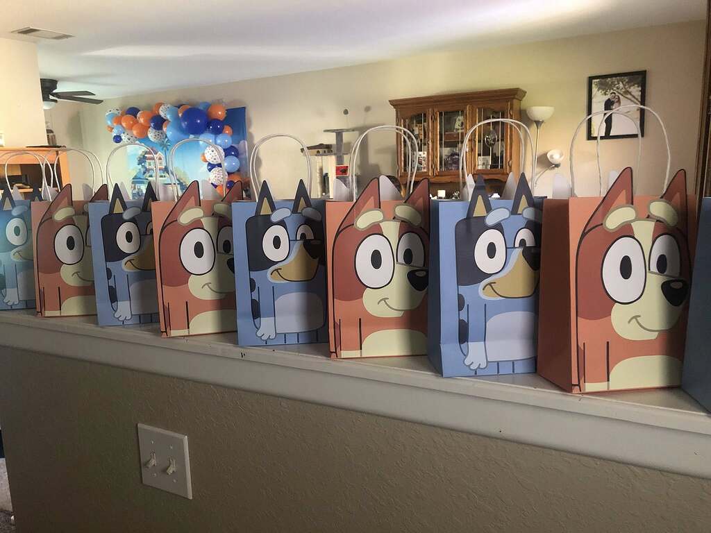 Row of Bluey and Bingo themed party favor bags displayed on a shelf.