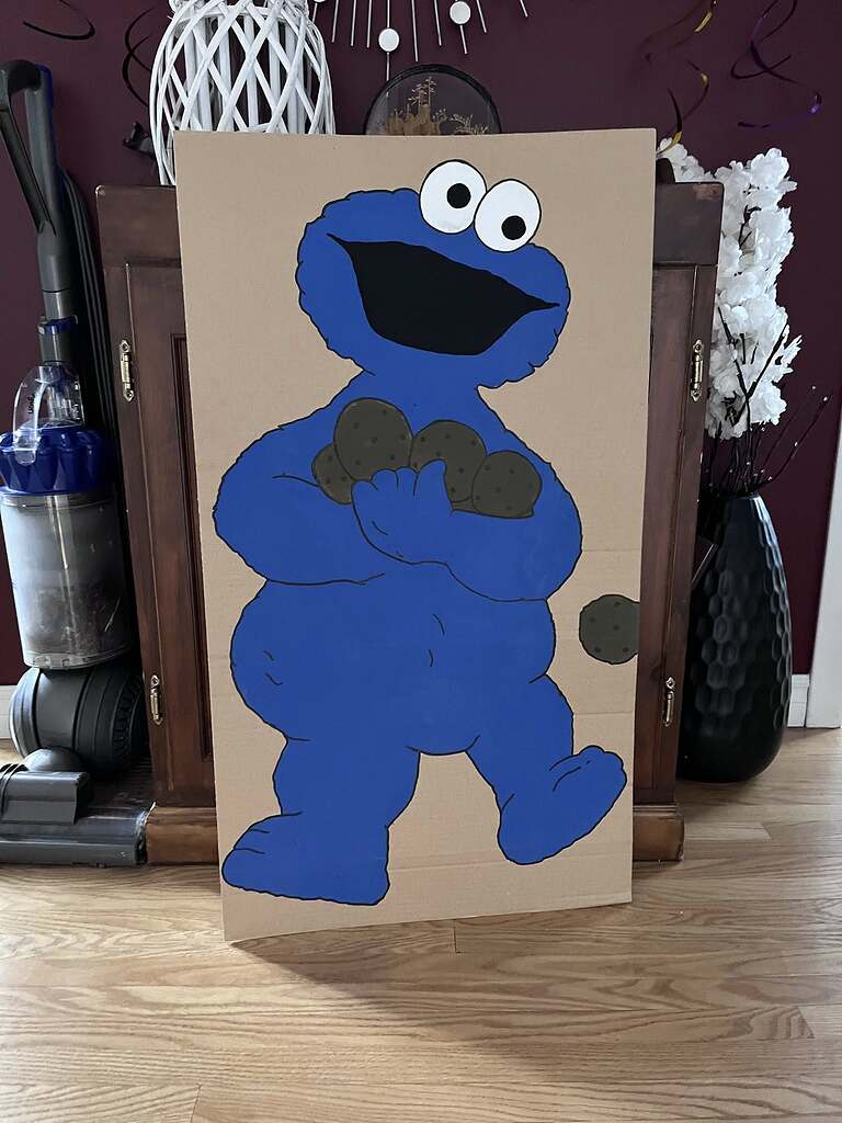 Cardboard cutout of Cookie Monster holding several chocolate chip cookies for a party game.