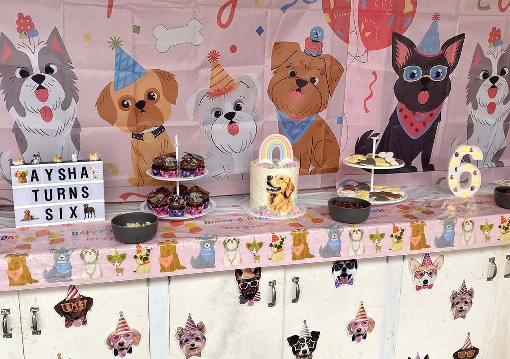 Dog-themed birthday party table setup featuring a cake with a golden retriever and a sign saying Aysha Turns Six