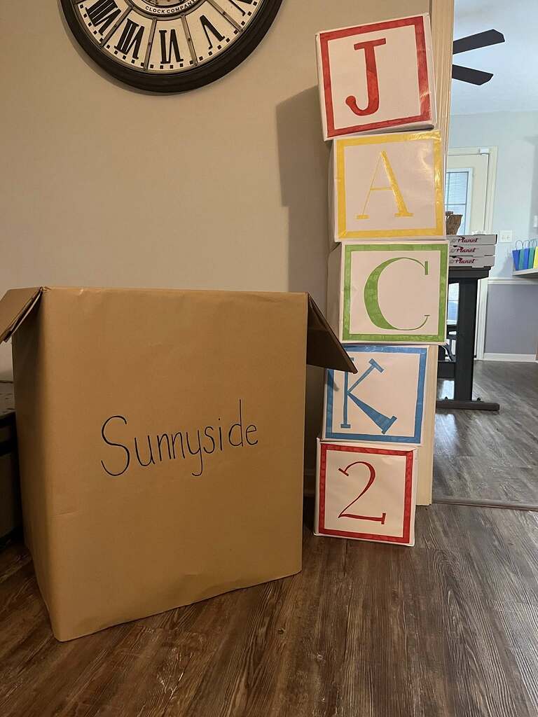 A cardboard box labeled Sunnyside next to a stack of blocks spelling Jack 2 for a party decoration.