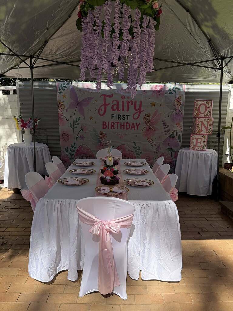 Fairy-themed first birthday party setup with decorated dining table, floral backdrop and ONE block display.