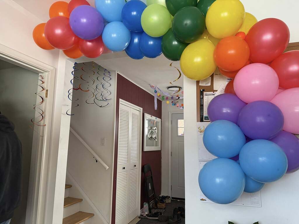 Rainbow colored balloon arch framing an indoor doorway