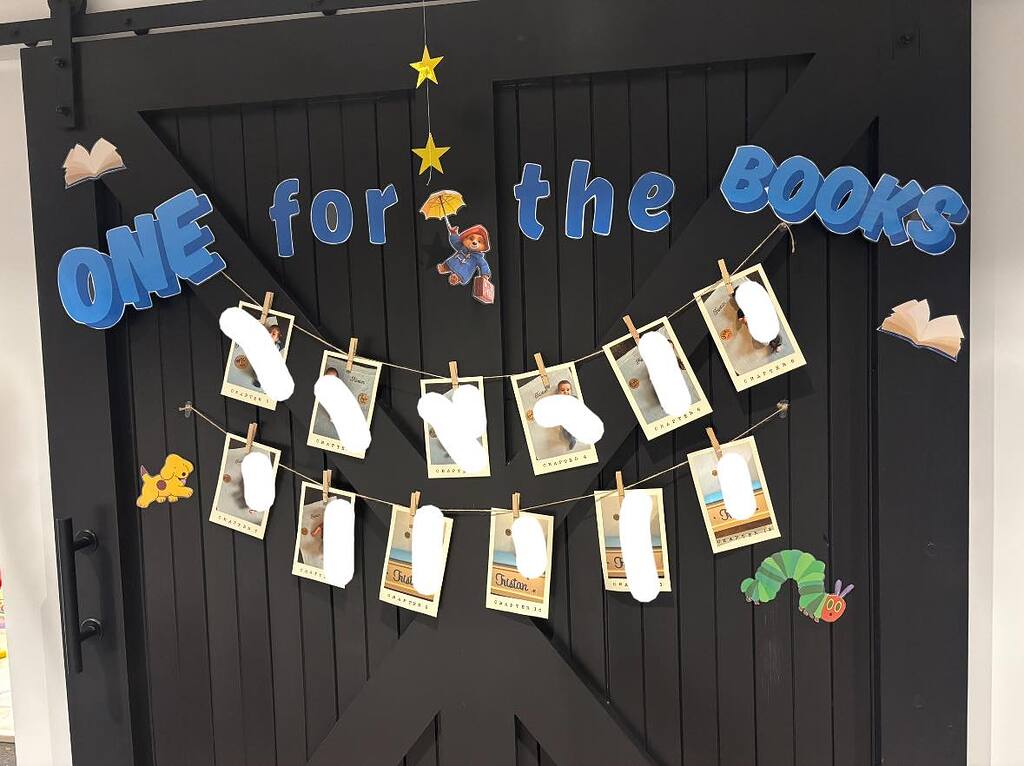 Classroom door decorated with the phrase One for the Books and hanging portraits of students labeled as chapters.