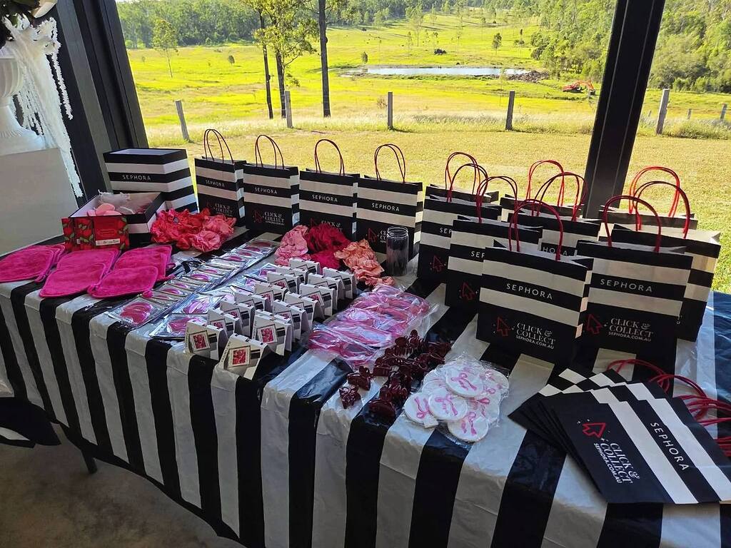 Table displaying Sephora Click and Collect bags and various pink beauty accessories.