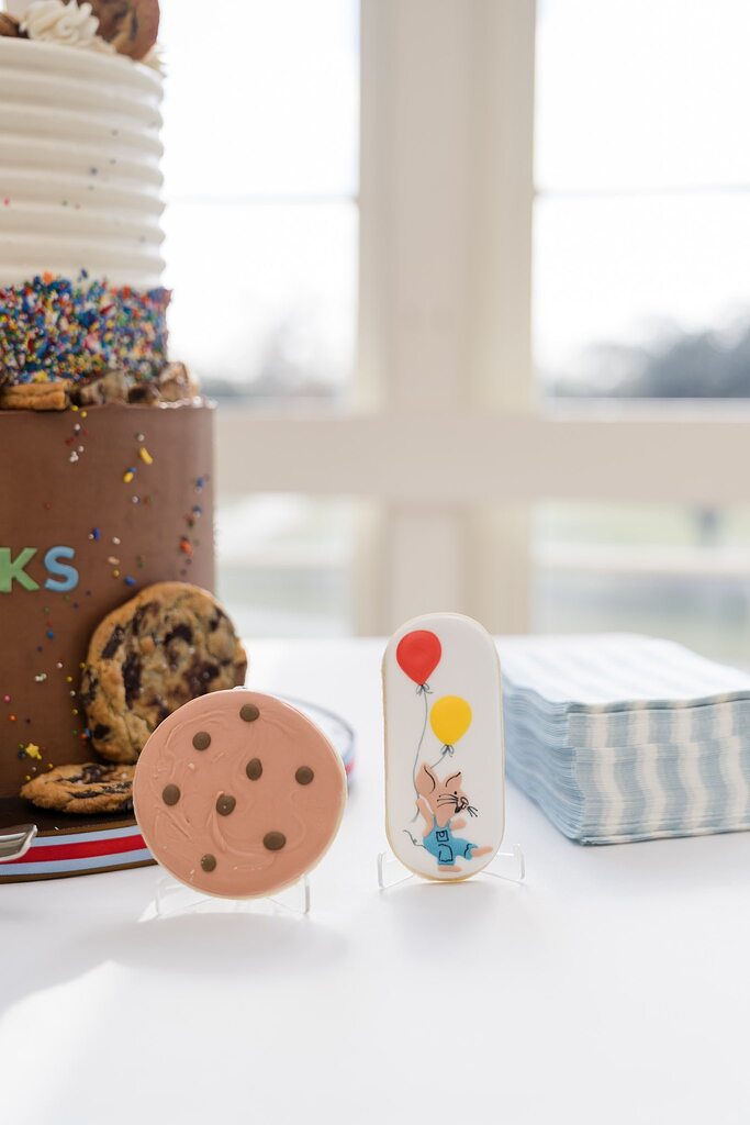 Decorated cookies next to a birthday cake with sprinkles and chocolate chips
