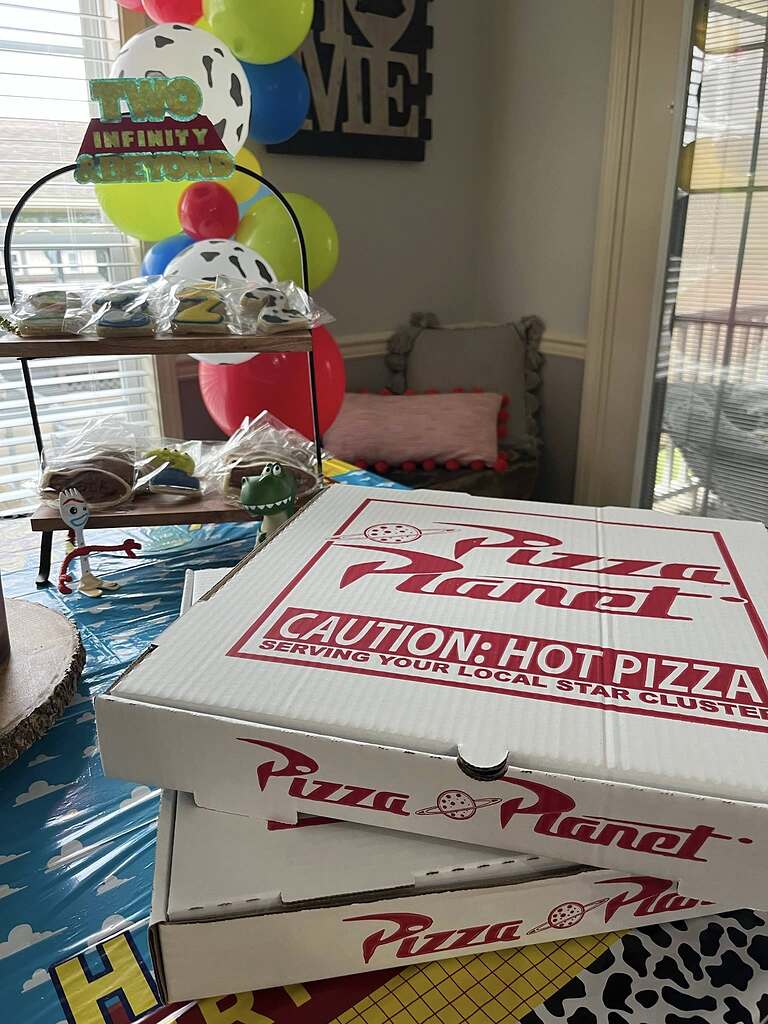 Stack of Pizza Planet themed pizza boxes on a Toy Story themed birthday party table.