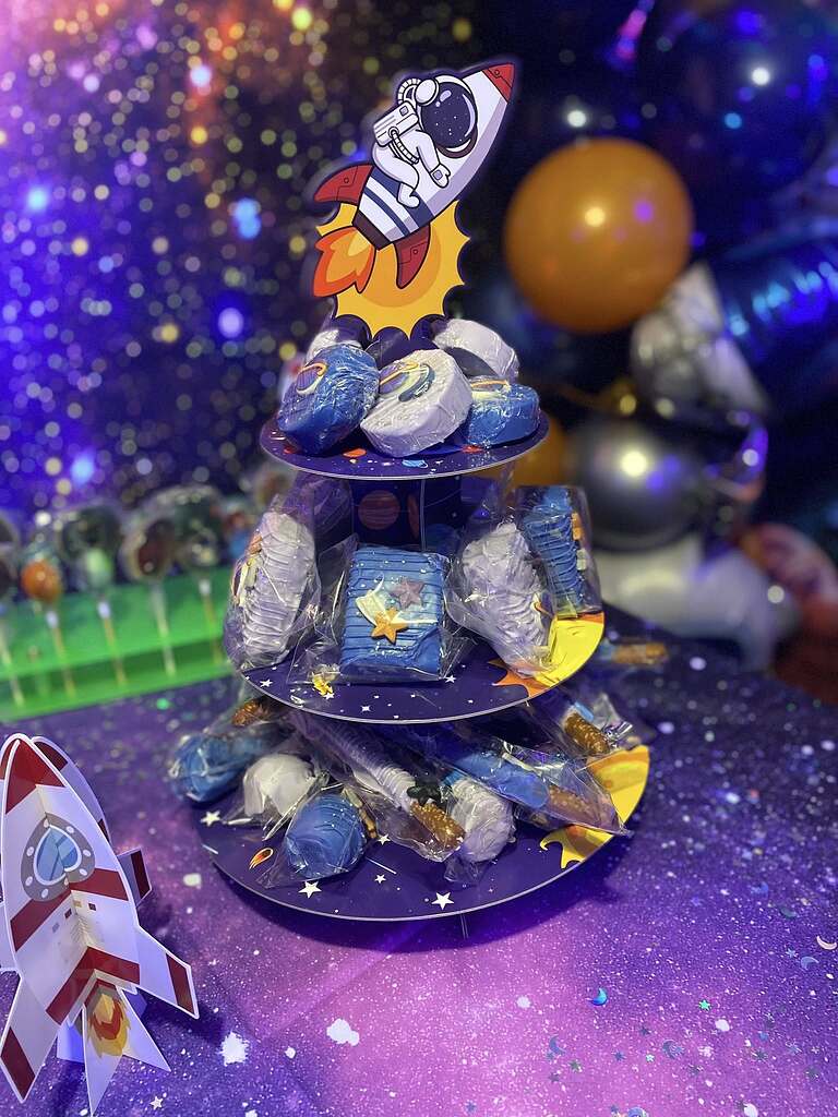 Three-tiered dessert display stand with blue and purple galaxy space-themed treats for a space-themed party.