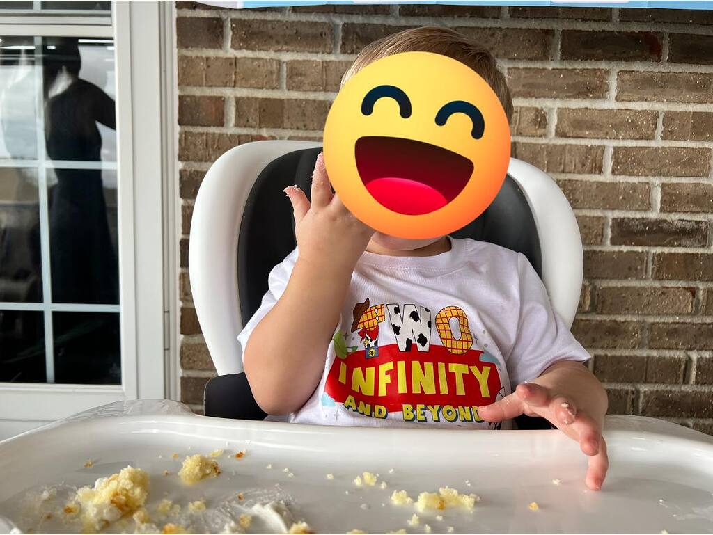 Toddler wearing a white T-shirt that says Two Infinity and Beyond during a birthday cake smash.