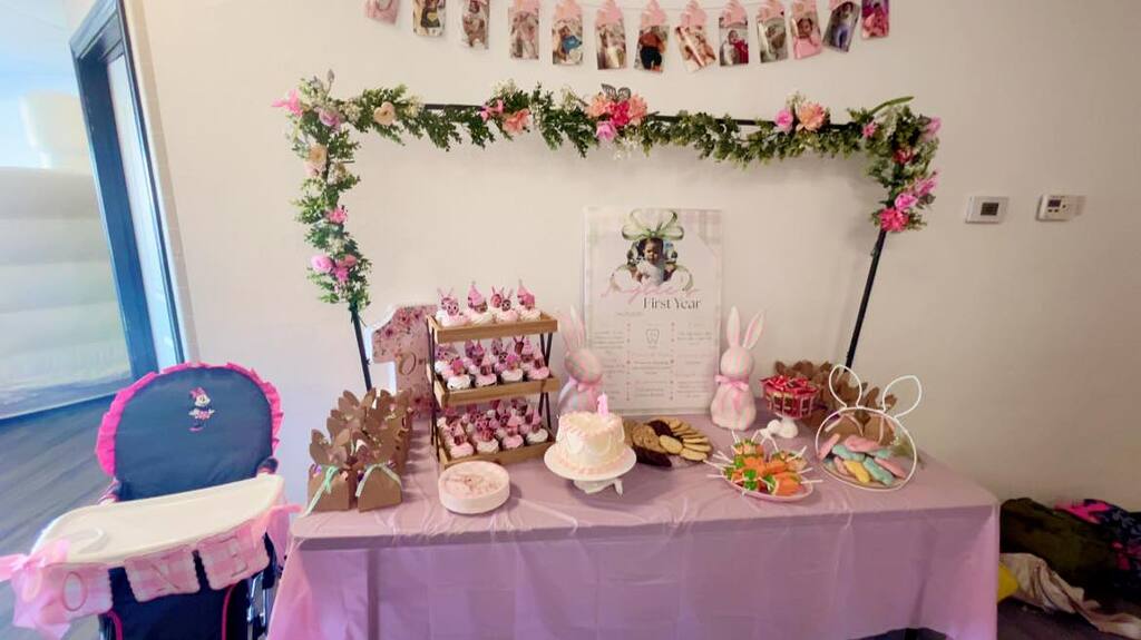 First birthday party table with a floral hoop, cupcakes, bunny decorations, and a birthday cake.