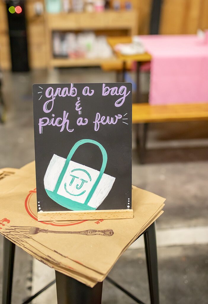 Chalkboard sign reading grab a bag and pick a few resting on a stack of paper bags.
