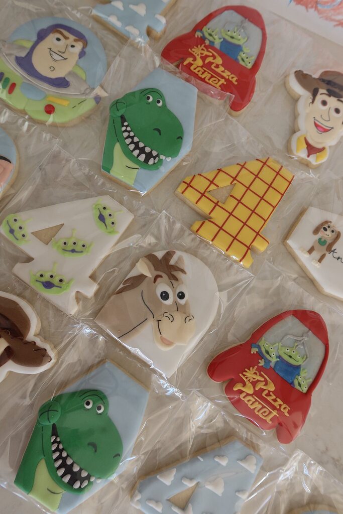 Assorted Toy Story themed decorated sugar cookies including characters, Pizza Planet rockets, and number fours.