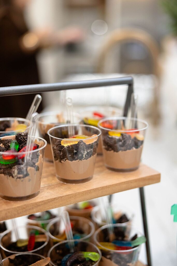 Individual chocolate pudding and cookie crumble dirt cups with gummy worms in clear plastic serving cups.