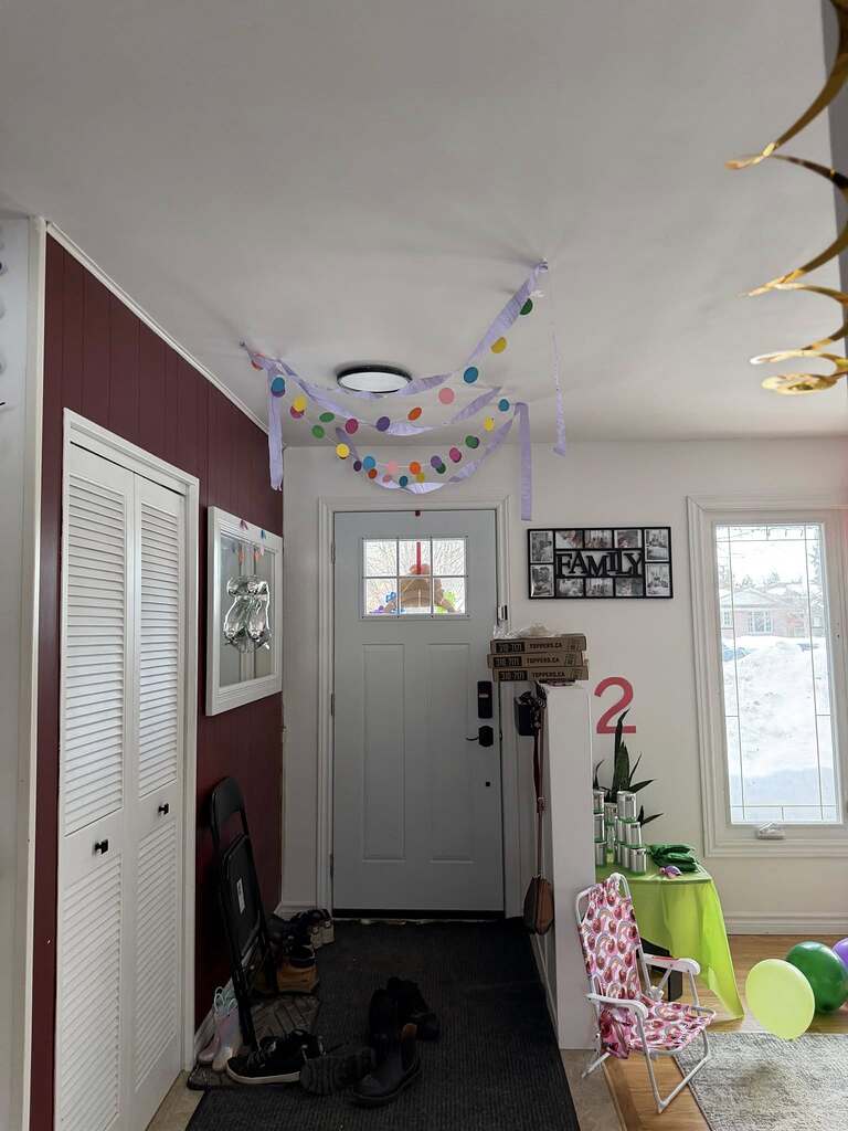 Entryway decorated for a second birthday party with streamers, a number two sign, and balloons.