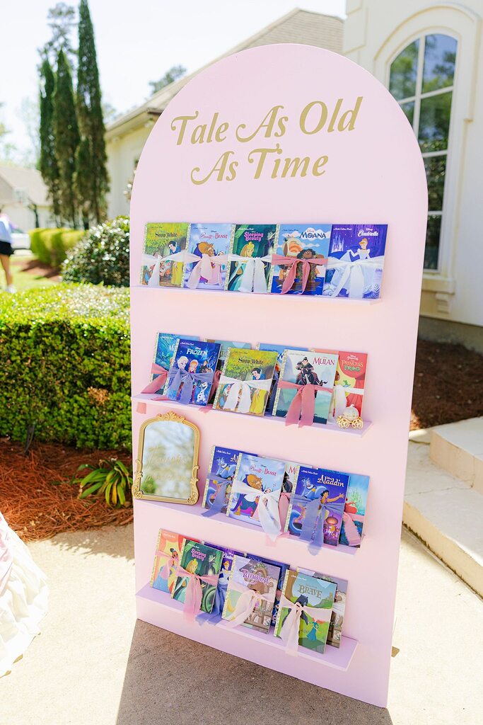 Pink display rack featuring a selection of Disney Little Golden Books tied with bows for a party favors table.