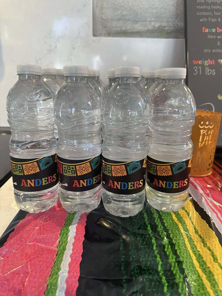 Several clear plastic water bottles with custom labels featuring colorful papel picado and the name Anders