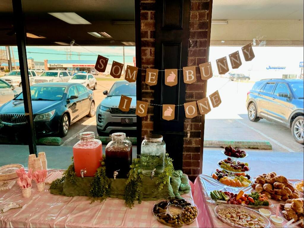 Some Bunny Is One birthday banner hanging above a snack and drink display table