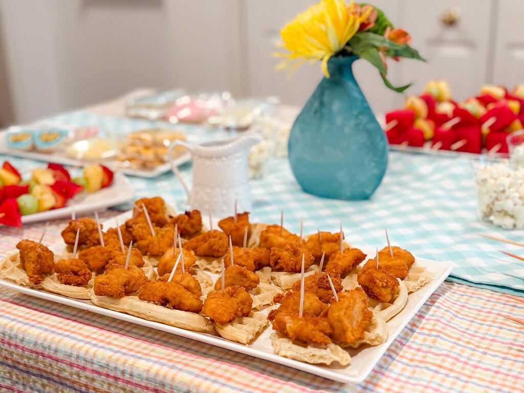 Platter of chicken and waffle appetizers with toothpicks on a checkered party table