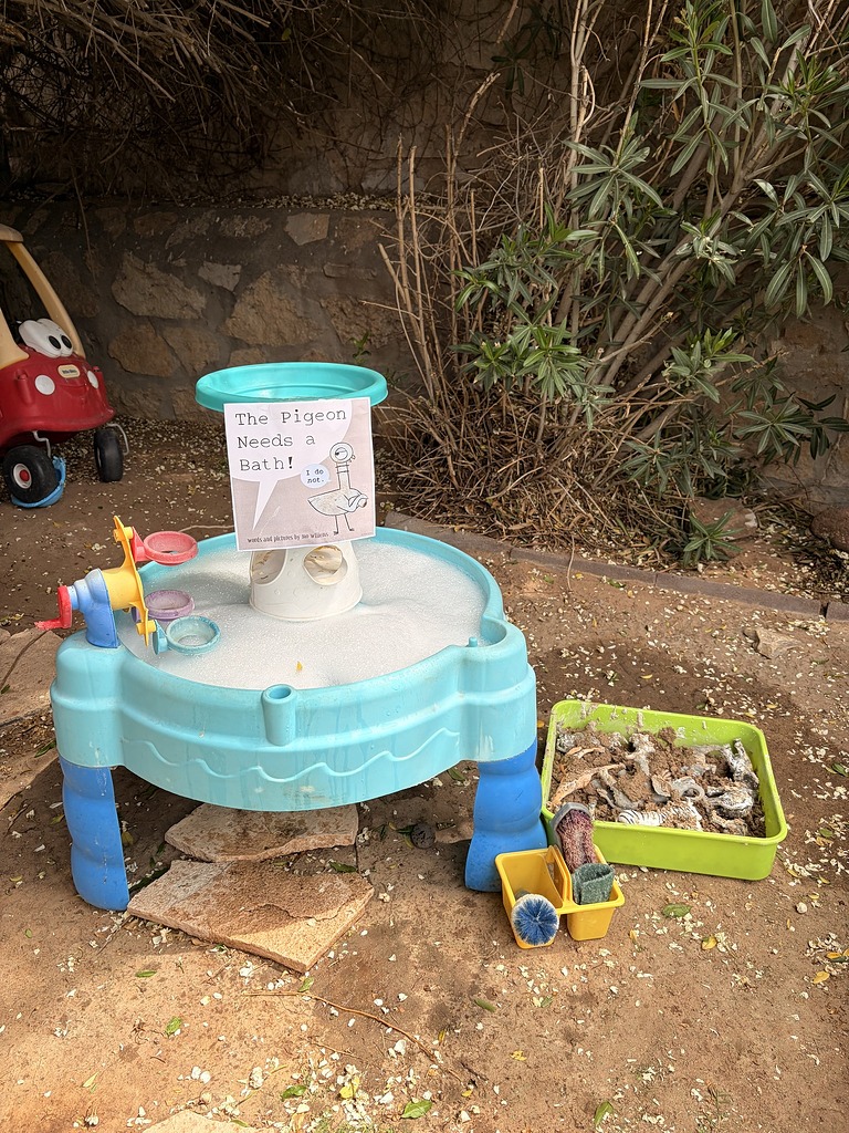 Kids water table featuring The Pigeon Needs a Bath book with messy plastic animals nearby