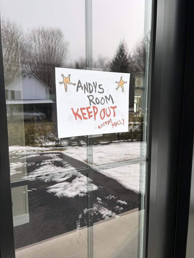 A handmade sign on a glass door that reads Andy's Room Keep Out except Molly with drawings of two sheriff badges.