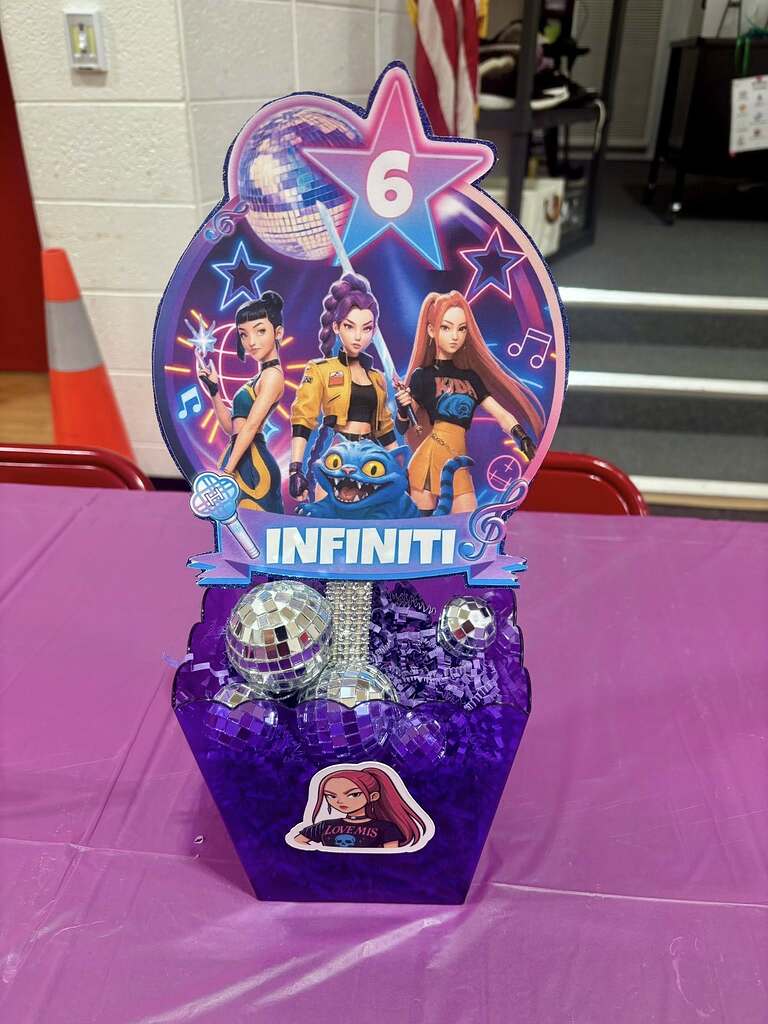 Custom K-pop themed party centerpiece featuring a pop-star cutout with the name Infiniti and a birthday age of 6.