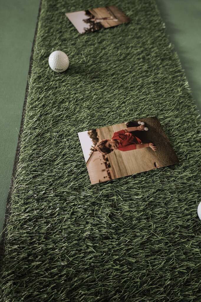 Indoor putting green mat with golf balls and a photograph of a child playing golf.