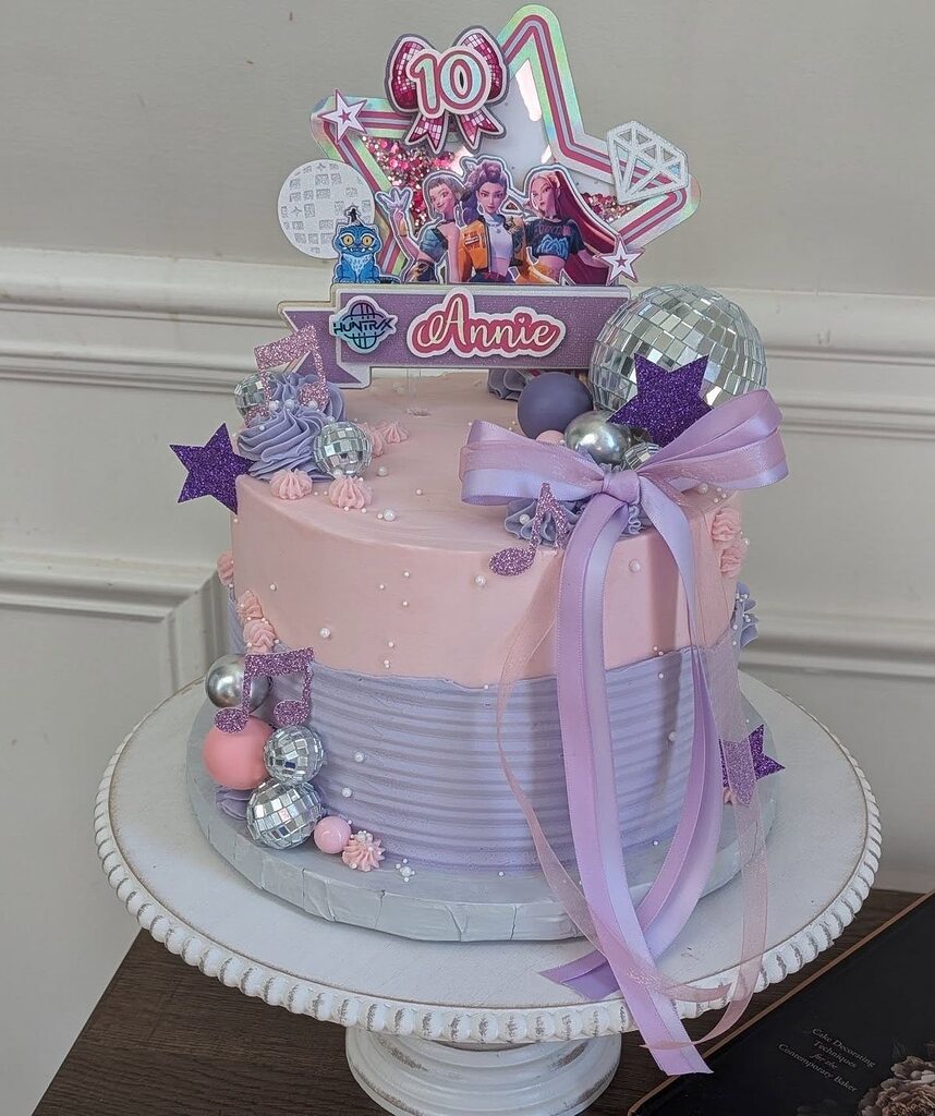 Two-tier pink and purple birthday cake decorated with disco balls, musical notes, and an Annie 10th birthday topper.
