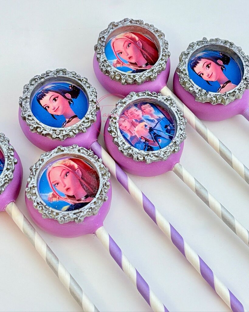 Custom lilac cake pops decorated with silver ornate frames featuring printed character edible images.