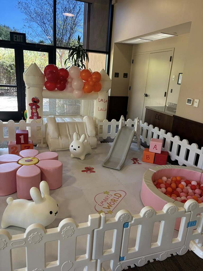 Soft play area for kids featuring an Elmo-themed bounce house, ball pit, slide, plush bunnies, and floor mats.