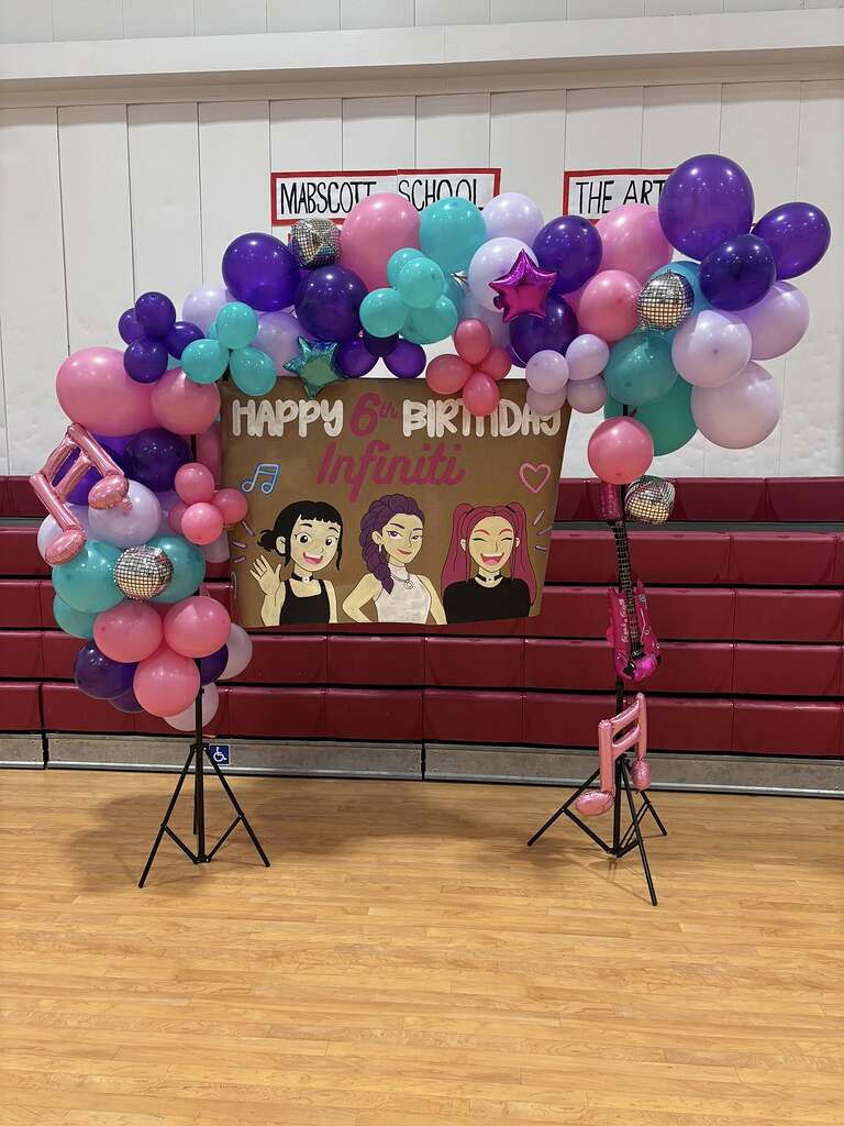 Rockstar-themed balloon arch backdrop with a sign saying Happy 6th Birthday Infiniti.