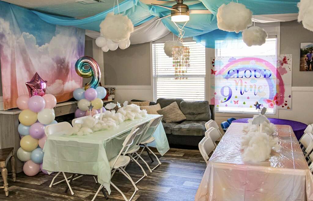 Cloud nine themed party decorations with rainbow banner, balloon arch, and clouds for a ninth birthday celebration.