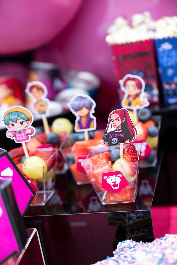 Fruit cups decorated with anime-style character party picks for a themed event.