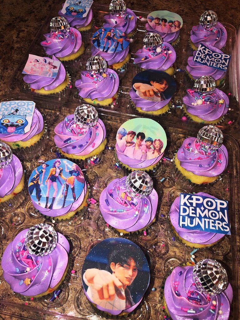 Cupcakes with purple frosting, disco ball toppers, and K-pop themed edible image decorations.